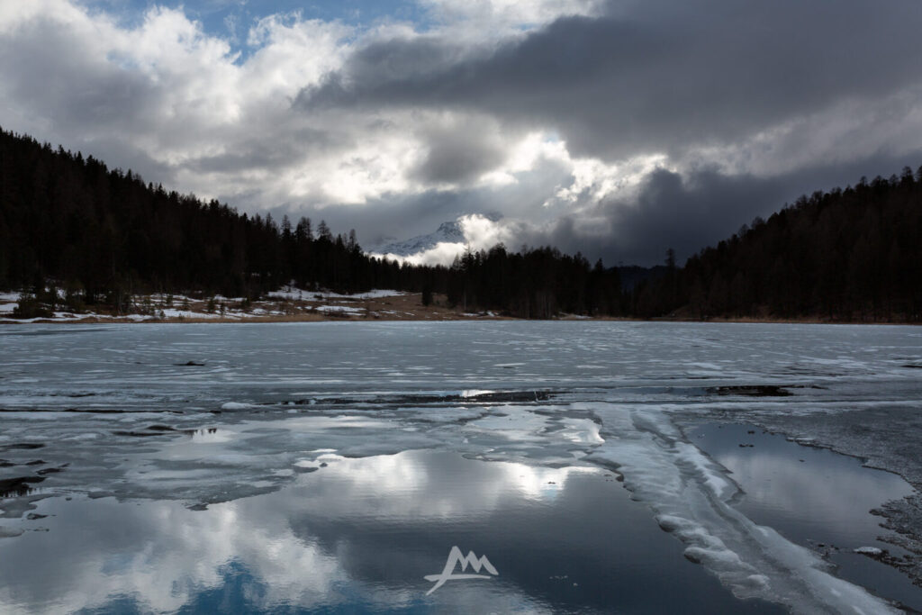 Riva di un lago di montagna con acqua scura e semi ghiacciata