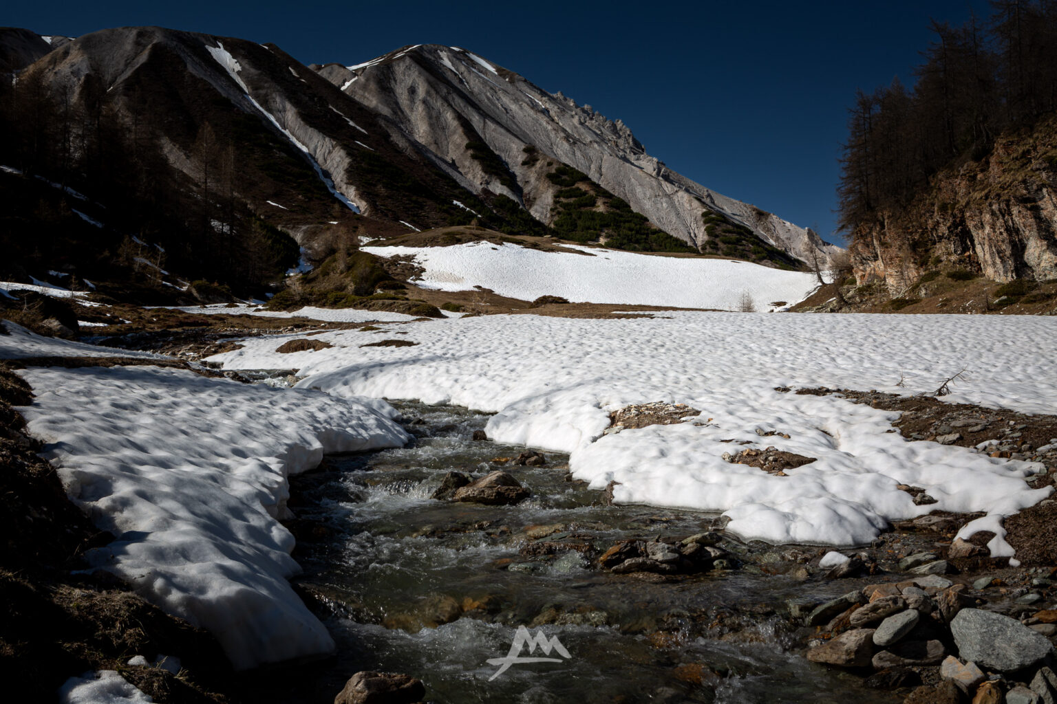 Neve primaverile che si scioglie in quota tra rocce e acqua