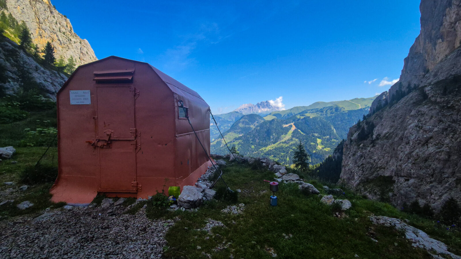 ivacco metallico in quota con sfondo di creste alpine e cielo sereno
