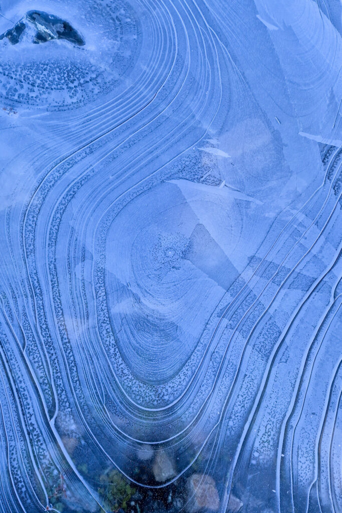 Dettaglio di una pozzanghera ghiacciata con cerchi concentrici azzurri