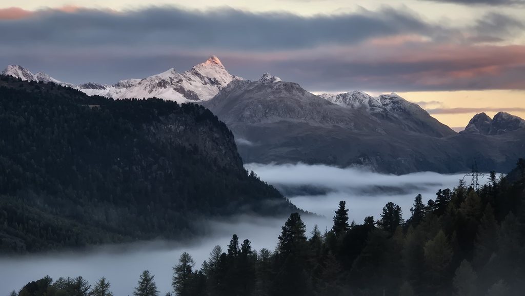 La cima del Piz Ot illuminata dal primo sole mentre la parete resta in ombra.